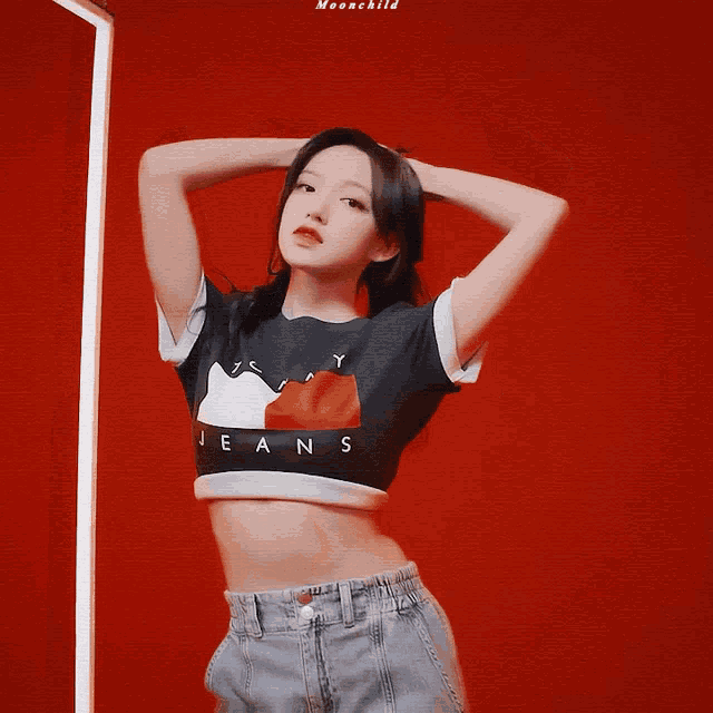 a woman wearing a tommy jeans crop top stands with her eyes closed
