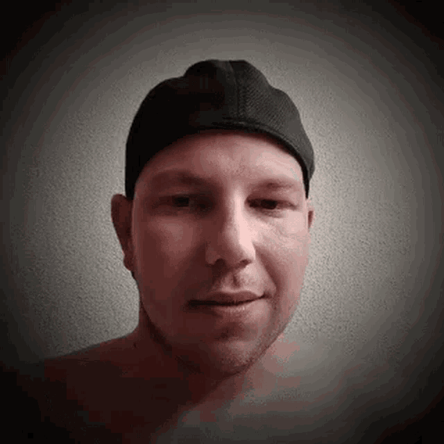 a shirtless man wearing a black hat is looking at the camera .