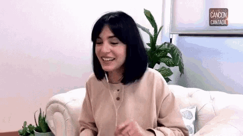 a woman is sitting on a couch wearing earphones and smiling .