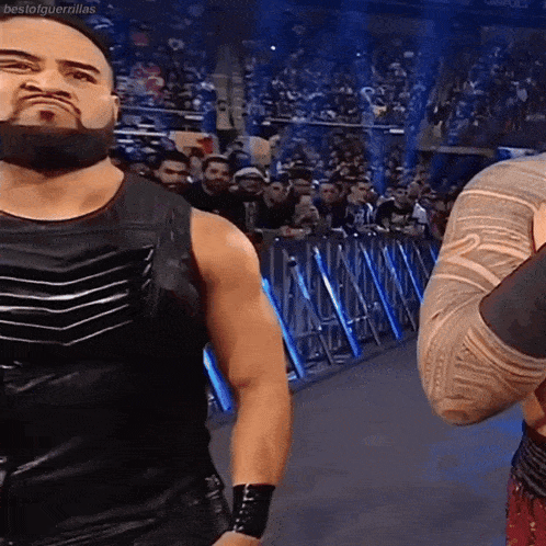 two wrestlers are standing in front of a crowd .