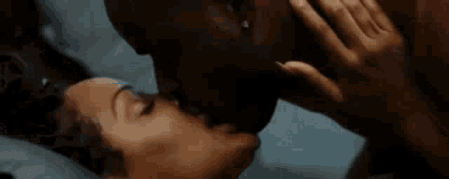 a man and woman are kissing in bed .
