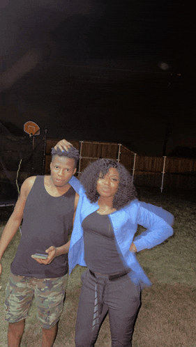 a man and a woman are posing for a photo in front of a basketball hoop