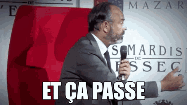 a man in a suit and tie is holding a microphone and says " et ca passe "