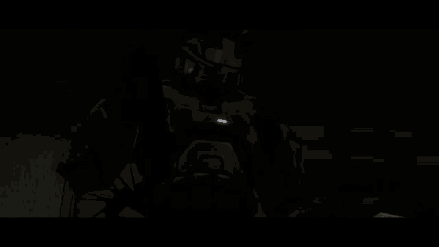 a man in a halo helmet is standing in the dark holding a gun .