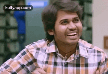 a young man in a plaid shirt is laughing and smiling .