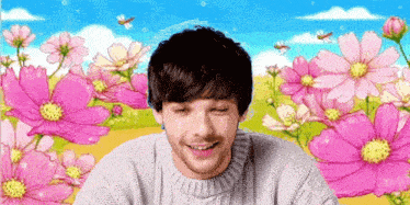 a man in a grey sweater is smiling in front of pink flowers