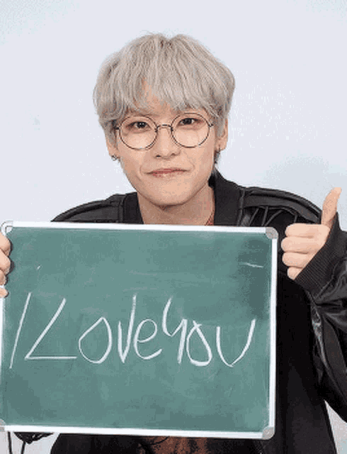 a young man wearing glasses is holding a sign that says " i love you "