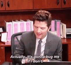 a man in a suit and tie is sitting at a desk in front of a laptop .