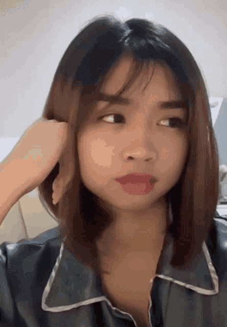 a close up of a woman 's face with her hand on her hair
