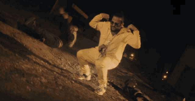 a man in a yellow tracksuit is squatting down and flexing his muscles