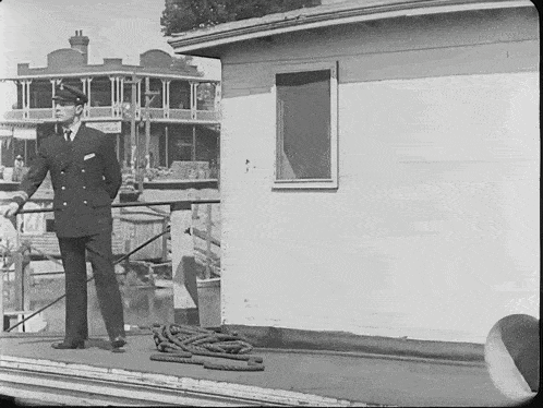 a black and white photo of a man standing in front of a building with a sign on it that says ' motel '