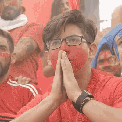 a man wearing glasses and a red face paint is praying
