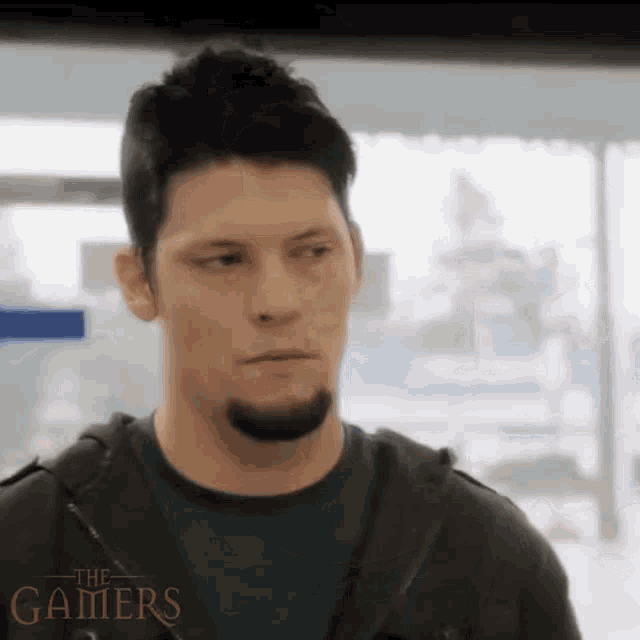 a man with a beard is standing in front of a sign that says " the gamers " on it