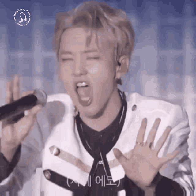 a man is singing into a microphone with his mouth open and his hands outstretched .