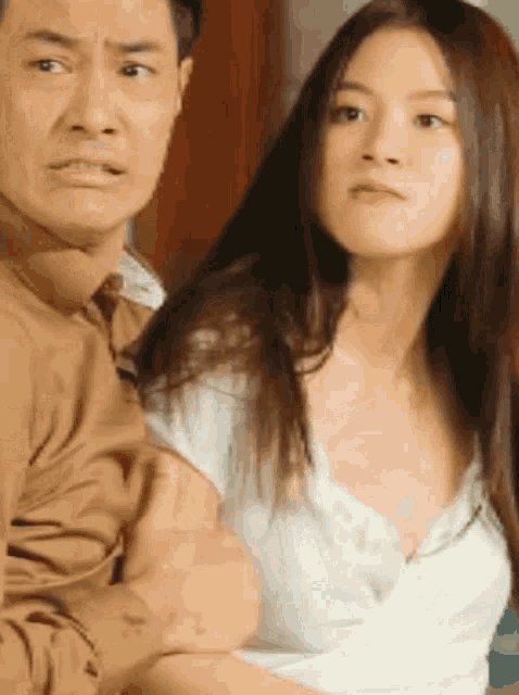 a man is holding a woman 's breast while she looks at the camera