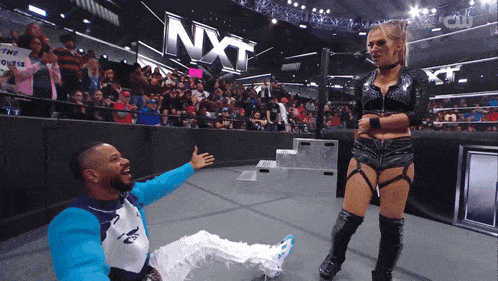 a female wrestler is standing next to a man who is laying on the floor