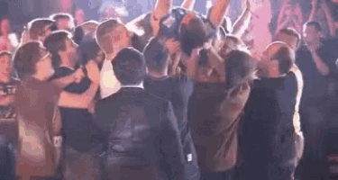 a group of people are dancing in a club and a man is being lifted in the air .