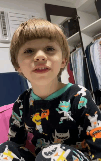 a young boy wearing a black pajama top with cats on it