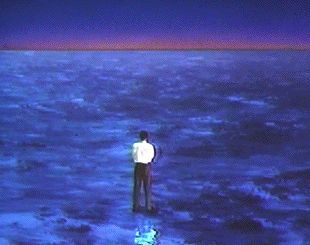 a man in a white shirt stands on a ledge looking at a city in the distance