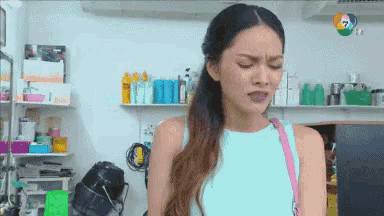 a woman in a blue tank top is making a funny face while standing in a room .