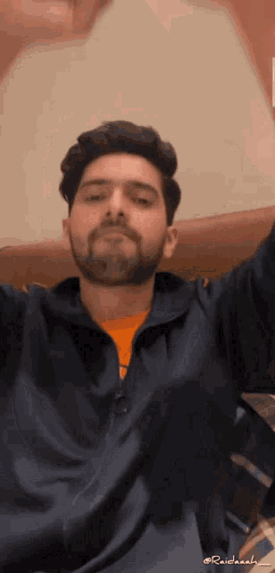 a man with a beard is taking a selfie with his hands in the air