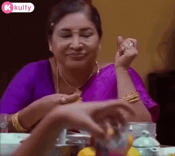 a woman in a purple dress is sitting at a table with a glass of water and a plate of food .