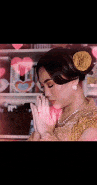 a woman with a flower in her hair is praying with her hands together
