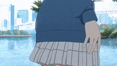 a girl in a blue sweater and a white pleated skirt stands in front of a body of water