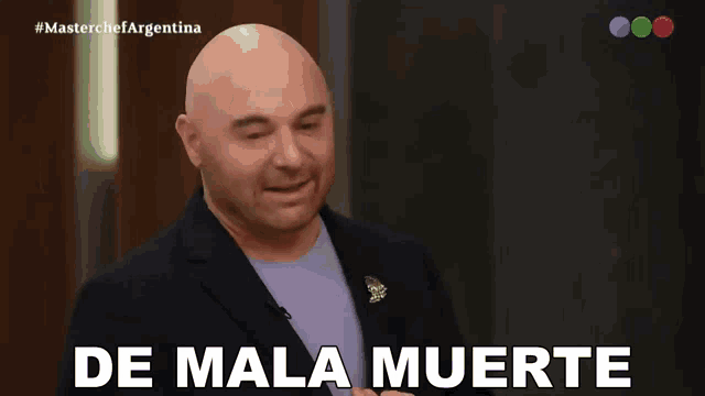a bald man in a suit is smiling with the words de mala muerte below him