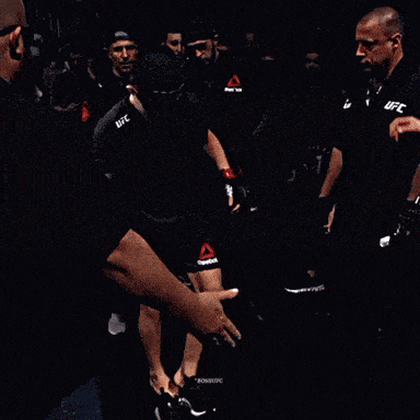 a man in a black shirt that says ufc stands in a dark room
