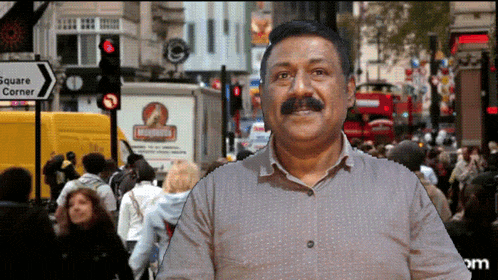 a man with a mustache stands in front of a sign that says square corner