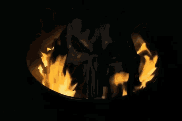 a man is standing in front of a large fire at night