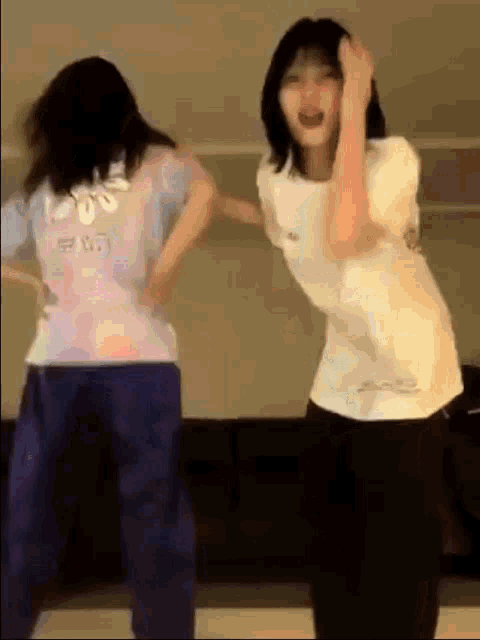 two girls are dancing together in a room and one of them is wearing a shirt that says ' a ' on it