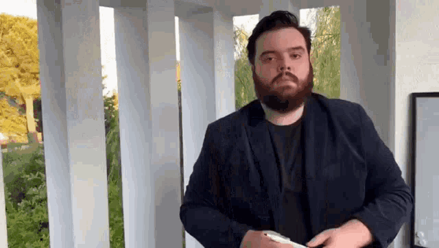a man with a beard and a suit is standing in front of a white railing .