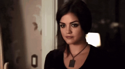 a woman wearing a black shirt and a black necklace is standing in a dark room .