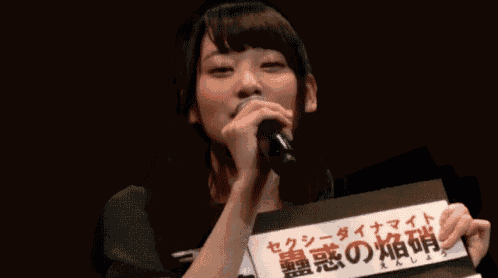 a woman is singing into a microphone while holding a piece of paper with chinese writing