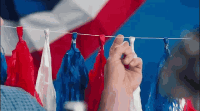 a person is hanging red white and blue decorations on a string