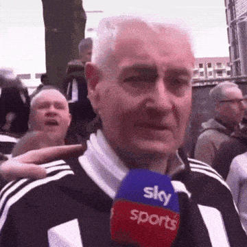 a man is holding a microphone that says sky sports on it