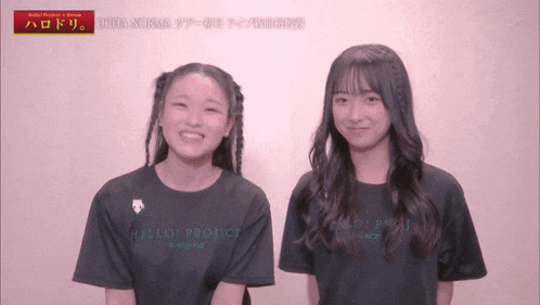 two girls wearing black hello project t-shirts smile for the camera