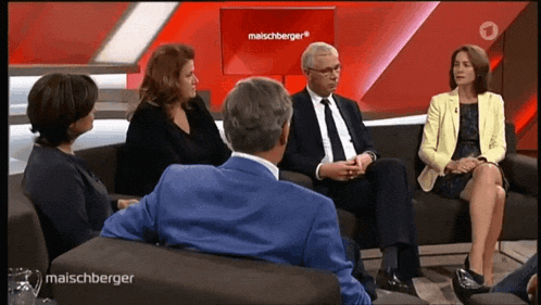 a group of people sitting on a couch in front of a red screen that says maischberger