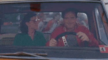a man and a woman in a car with the words " with my hot dogs flyin " on the bottom