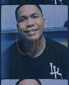 a man wearing a black shirt with the letter lx on it is smiling