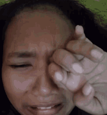 a woman is crying with her eyes closed and her hand covering her face .