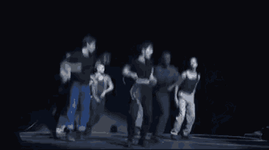 a group of people are dancing in a dark room