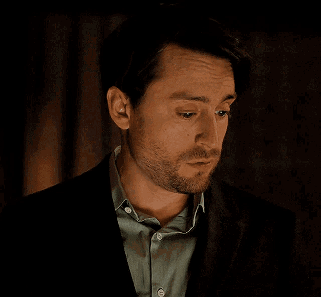 a man with a beard wearing a suit and a green shirt