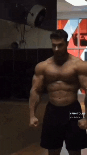 a muscular man is flexing his muscles in a gym .
