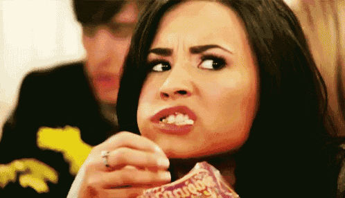 a woman is eating a bag of doritos chips and making a face .