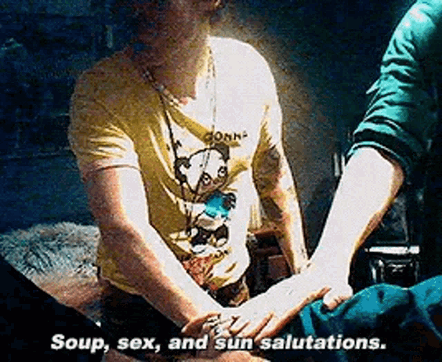 a man in a yellow shirt is holding another man 's hand and saying " soup sex and sun salutations "