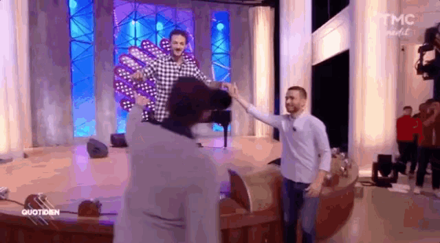 a man is giving another man a high five on a stage in front of a tmc logo