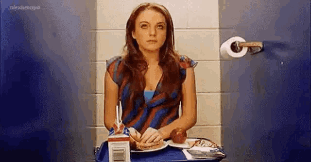a woman is sitting at a table with a plate of food .
